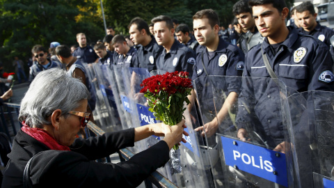 Una manifestante muestra un ramo de flores en la barricada policial deslpegada frente a la concentración en recuerdo de las víctimas del doble atentado suicida en Ankara. REUTERS/Umit Bektas Una manifestante muestra un ramo de flores en la barricada policial deslpegada frente a la concentración en recuerdo de las víctimas del doble atentado suicida en Ankara. REUTERS/Umit Bektas