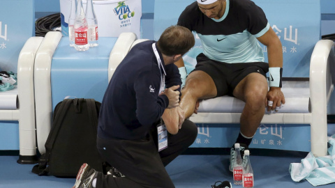 Rafa Nadal recibe atención de un masajista en su pie durante la final del Open de Pekín. REUTERS/Jason Lee