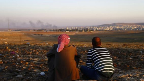 Dos turcos kurdos observan como el humo se eleva sobre la ciudad Siria de Kobani desde una colina durante un combate. REUTERS Dos turcos kurdos observan como el humo se eleva sobre la ciudad Siria de Kobani desde una colina durante un combate. REUTERS