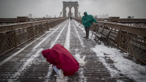 Dos turistas atraviesan el puente de Brooklyn en medio de la nevada. EFE/Andrew Kelly