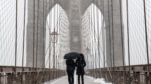 Dos personas caminan bajo la nieve por el puente de Brooklyn. EFE/ANDREW KELLY