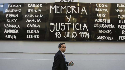 Un hombre camina bajo un cartel durante una manifestación para exigir justicia tras la muerte del fiscal argentino Alberto Nisman en el exterior de la sede de la AMIA en Buenos Aires. - EFE Un hombre camina bajo un cartel durante una manifestación para exigir justicia tras la muerte del fiscal argentino Alberto Nisman en el exterior de la sede de la AMIA en Buenos Aires. - EFE