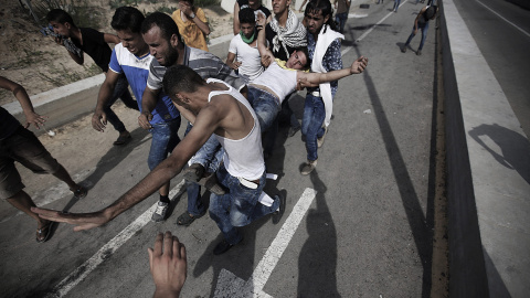Jóvenes palestinos trasladan a un compañero herido durante un enfrentamiento con soldados israelíes cerca del cruce de Erez, en el norte de la Franja de Gaza, Palestina. EFE/Mohammed Saber