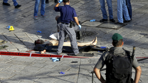 Policías israelíes comprueban el cuerpo de un hombre palestino que intentó apuñalar a la policía y fue abatido a tiros según un portavoz de la policía israelí, en una entrada a la amurallada Ciudad Vieja de Jerusalén, 14 de octubre de 2015.