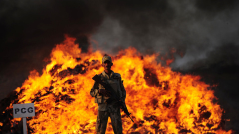 Un soldado paquistaní de la Fuerza contra Narcóticos se encuentra al lado de un montón de drogas en llamas que fueron incautadas en las afueras de Karachi, el 15 de octubre de 2015. AFP/ASIF HASSAN