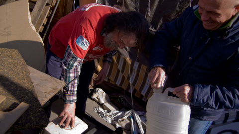 Dos trabajadores echan gasolina al generador que proporciona electricidad al campamento contra el cierre de la planta de Coca-Cola en Fuenlabrada. -JAIRO VARGAS