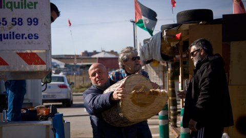 Los trabajadores descargan la leña que les trae un trabajador municipal de Fuenlabrada al campamento contra el cierre de la embotelladora de Coca-Cola- JAIRO VARGAS
