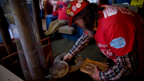Uno de los trabajadores acampados frente al planta de Coca-Cola, en Fuenlabrada, echa leña a la estufa. -JAIRO VARGAS
