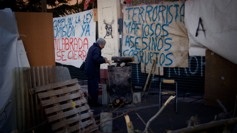 Un trabajador añade leña en un bidón para calentarse mientras hace guardia en uno de los accesos a la fábrica de Coca-Cola en Fuenlabrada. -JAIRO VARGAS