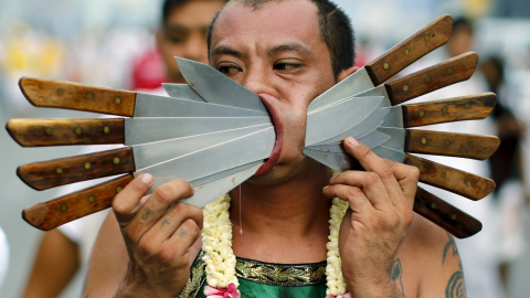 Un devoto del santuario chino Samkong camina con cuchillos que le atraviesan las mejillas durante una procesión que celebra el festival anual vegetariano en Phuket, Tailandia, 16 de octubre de 2015. REUTERS / Jorge Silva