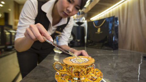 Una empleada del hotel Ritz-Carlton de  Almatý, en Kazajistán, sirve un capuchino con oro comestible al precio de 9,5 euros. / SHAMIL ZHUMATOV (REUTERS)