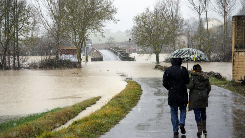 Varias personas caminan por la carretera de acceso al pueblo de Villodas que se encuentra inundada debido al desbordamiento del río Zadorra, tras las lluvias registradas en la región. -EFE/ADRIAN RUIZ DE HIERRO