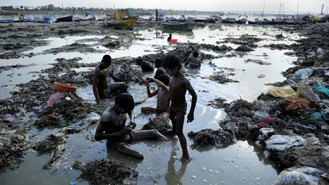 Varios hombres buscan oro y monedas en el agua contaminada del río Ganga, en Sangam. AFP Varios hombres buscan oro y monedas en el agua contaminada del río Ganga, en Sangam. AFP