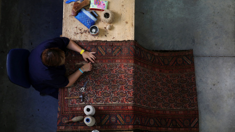 Un restaurador repara con métodos artesanales una alfombra en la Real Fábrica de Tapices. REUTERS / Susana Vera