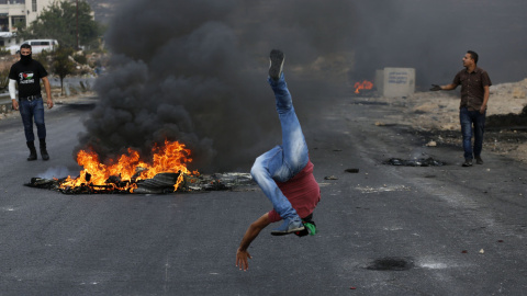 Un manifestante palestino se burla de los guardias israelíes en la frontera durante los enfrentamientos cerca del asentamiento judío de Beit El, al norte de Ramallahon. AFP PHOTO / ABBAS MOMANI