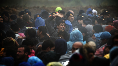 Agentes de policía croatas montan guardia mientras los emigrantes esperan para entrar en Croacia desde la frontera entre Serbia y Croacia, cerca del pueblo de Berkasovo, el 19 de octubre de 2015. AFP/ANDREJ ISAKOVIC