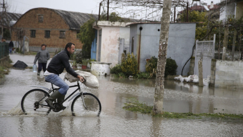 Un hombre monta en bicicleta por una calle inundada. /EFE