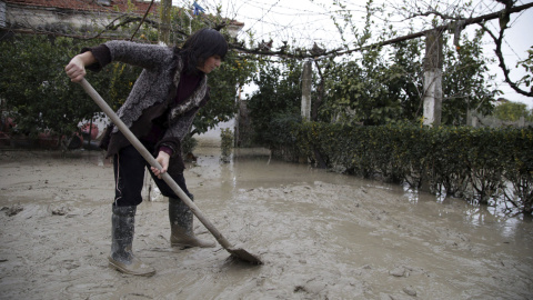 Una mujer quita lodo con una pala después de que su casa resultara inundada por la lluvia. /EFE