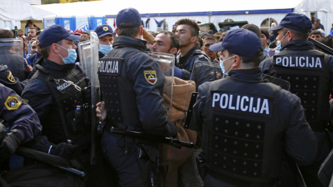 Agentes eslovenos montan un cordón policial en un paso fronterizo. - REUTERS Agentes eslovenos montan un cordón policial en un paso fronterizo. - REUTERS