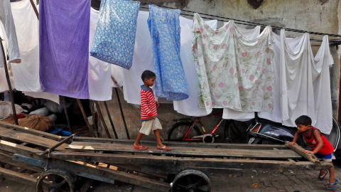 Unos niños juegan con un carromato en un suburbio de Mumbai en India. /REUTERS