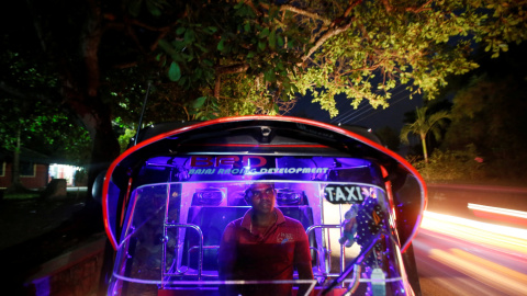 Un conductor de tuk tuk espera por clientes dentro de su vehículo en el arcén de una carretera de Kesbewa, en Sri Lanka. /REUTERS