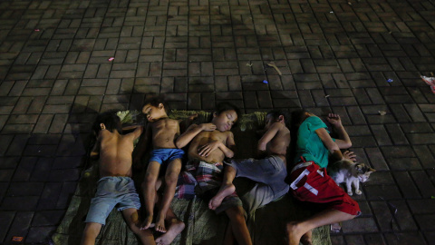 Niños duermen en medio de la carretera cerca de una iglesia de Manila. / REUTERS