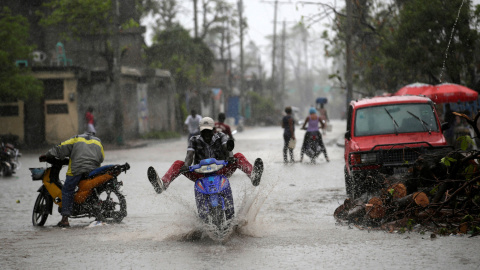 Un hombre conduce una moto sobre el suelo mojado por la lluvia tras el Huracán Matthew en Los Cayos, Haití. / REUTERS