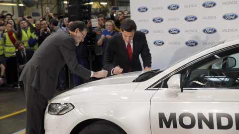 El presidente del Gobierno, Mariano Rajoy, y el presidente mundial de Ford, Mark Fields, firman sobre un vehículo durante la visita que han realizado a la fábrica de Ford en Almussafes, en la Comunidad Valenciana. EFE/Kai Försterling