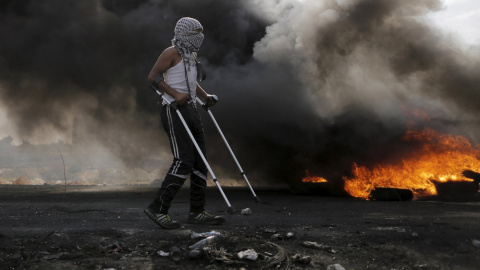 Un manifestante palestino camina con muletas durante los enfrentamientos con las tropas israelíes cerca del asentamiento judío de Bet El, cerca de la ciudad cisjordana de Ramala. REUTERS / Ammar Awad