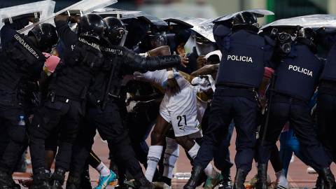 Policías antidisturbios protegen al jugador de Ghana John Boye de los objetos lanzados por los fans de Guinea Ecuatorial, en un partido de la Copa Africana de Naciones. /AMR ABDALLAH DALSH (REUTERS)