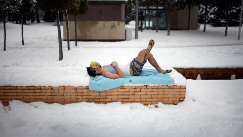Un joven sobre una toalla de playa, en un parque cubierto de nieve en Vitoria. /VICENTE WEST (REUTERS)
