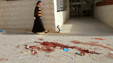 Una mujer pasa cerca de donde dos presuntos atacantes palestinos fueron abatidos a tiros por la policía israelí después de intentar subir a un autobús que transportaba niños tras apuñalar a un hombre israelí, en Beit Shemesh al oeste de Jer