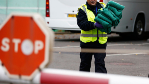 Un funcionario de la fuerza fronteriza lleva mantas utilizadas por los niños internos en La Jungla de Calais.- PETER NICHOLLS (REUTERS)
