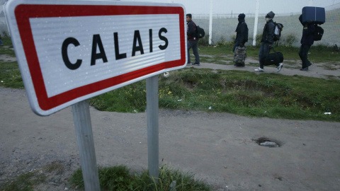 Varios inmigrantes cargan con sus pertenencias durante la evacuación de la 'Jungla' de Calais. REUTERS/Pascal Rossignol