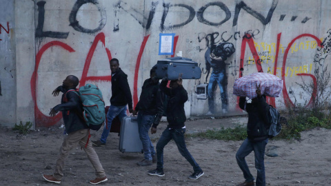 Un grupo de refugiados porta sus pertenencias durante la evacuación de la 'Jungla' de Calais. REUTERS/Pascal Rossignol