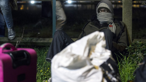 Unos inmigrantes esperando los autobuses que evacúan la 'Jungla' de Calais. EFE/EPA/Etienne Laurent
