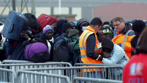 Refugiados hacen cola junto a las vallas antes de ser evacuados de la 'Jungla' de Calais. REUTERS
