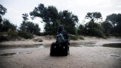 Un inmigrante espera junto a su equipaje en el campamento conocido como la 'Jungla' durante su desmantelamiento en Calais, Francia. EFE/Etienne Laurent