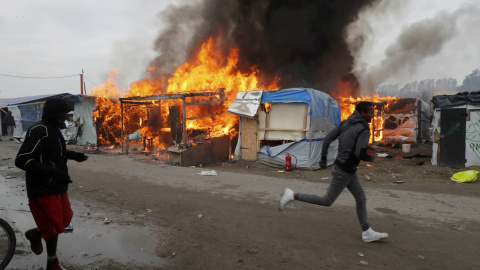 Varios inmigrantes se alejan del incendio en una de las tiendas de la Jungla. - REUTERS Varios inmigrantes se alejan del incendio en una de las tiendas de la Jungla. - REUTERS