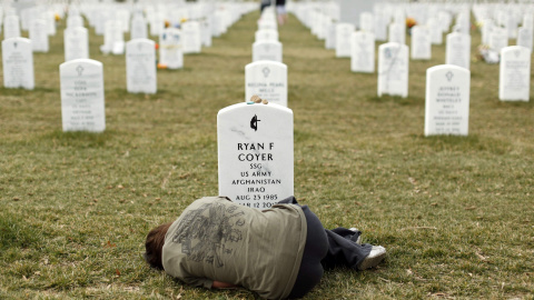 Lesleigh Coyer, de 25 años, tumbado delante de la tumba en el Cementerio Nacional de Arlington de su hermano, Ryan Coyer, que sirvió con el Ejército de EEUU en Irak y Afganistán (11 de marzo de 2013). REUTERS / Kevin Lamarque