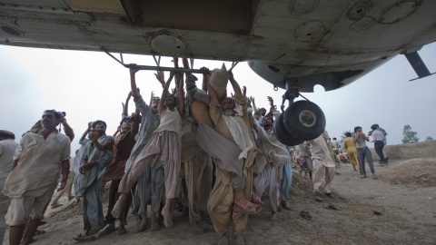 Víctimas de las inundaciones Marooned, en Paquistán, tratan de agarrarse a las barras laterales de un helicóptero del Ejército que transportaba alimentos para los damnificados (7 de agosto de 2010). REUTERS / Adrees Latif