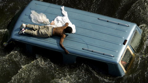Un hombre se aferra a la parte superior de un vehículo antes de ser rescatado por la Guardia Costera de Estados Unidos de las calles inundadas de Nueva Orleans, en las secuelas del huracán Katrina (4 de septiembre de 2005). REUTERS / Robert