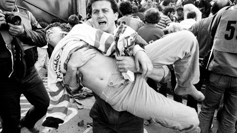 Un aficionado traslada a uno de los heridos en la avalancha en el estadio Heysel de Bruselas, en la final de la copa de Europa entre  la Juventus y el Liverpool, que provoó la muerte de 39 personas y 600 heridos (29 de mayo de 1985). REUTER