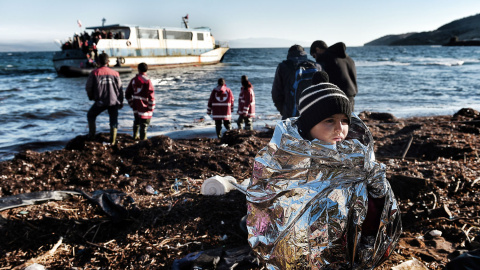 Un niño intenta entrar en calor con una manta al llegar a la isla griega de Lesbos. AFP / ARIS MESSINIS