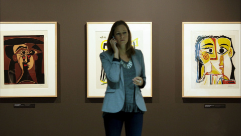 Una mujer habla por teléfono ante tres de los linograbados que Pablo Picasso dedicó a su mujer Jacqueline Roque,que forman parte de la exposición organizada por la Fundación Bancaja, que reúne mas de 200 obras del artista malagueño, entre g