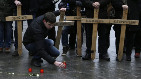 Un hombre coloca en el suelo una vela, junto a las cruces que recuerdan a los muertos en la plaza de Maida, en Kiev, en las revueltas contra el el régimen de Víctor Yanukovich. REUTERS/David W Cerny Un hombre coloca en el suelo una vela, junto a las cruces que recuerdan a los muertos en la plaza de Maida, en Kiev, en las revueltas contra el el régimen de Víctor Yanukovich. REUTERS/David W Cerny