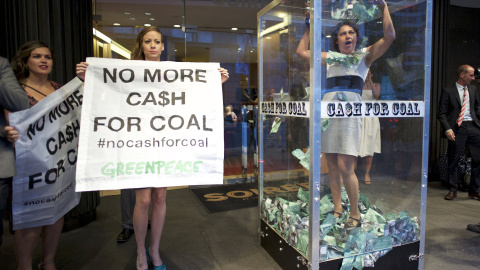 Una manifestante de Greenpeace intenta atrapar el dinero falso en una cabina junto como protesta contra la industria minera de Australia. REUTERS/Jason Reed