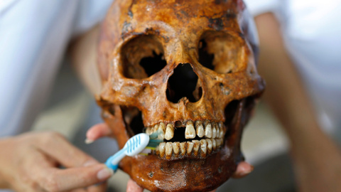 Un voluntario limpia un cráneo de los restos no identificados de una fosa común que están siendo exhumados en el cementerio de la fundación funeraria Poh Teck Tung, en la provincia de Samut Sakhon (Tailandia). Se trata de los restos mortale