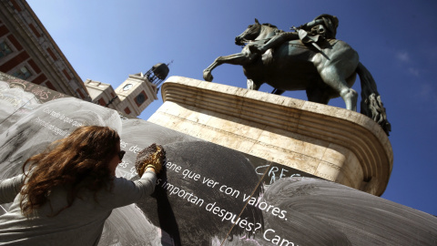 Una mujer limpia una pizarra mural instalada en la Puerta del Sol de Madrid, que parte de una iniciativa de la ONG "Alianza por la Solidaridad". EFE/Javier Lizón