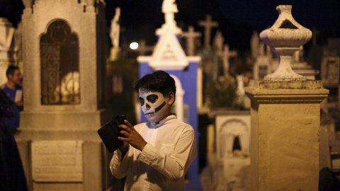 Un niño con la cara pintada de calavera usa su móvil mientras participa en el "Paseo de las Animas" en el día de los difuntos en Mérida, México. REUTERS/Lorenzo Hernandez